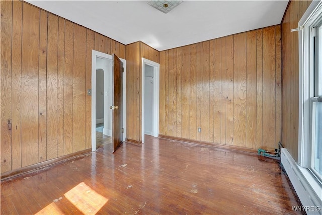 10470 Main St, North Collins, NY 14111 - empty room with baseboard heating, wood walls, and wood finished floors