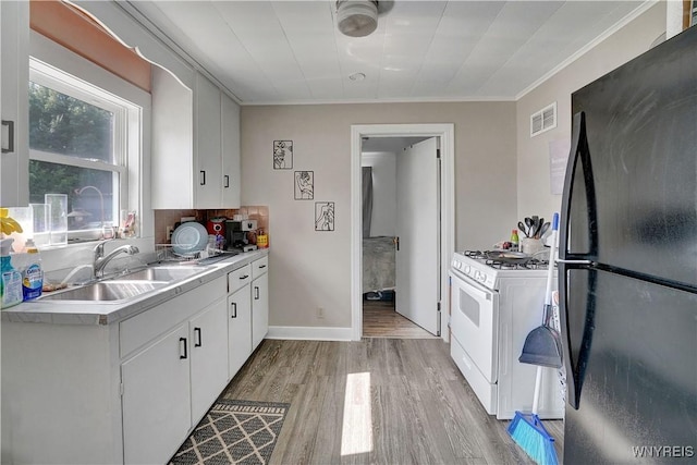 10470 Main St, North Collins, NY 14111 - kitchen with freestanding refrigerator, white gas stove, light wood finished floors, light countertops, and white cabinets