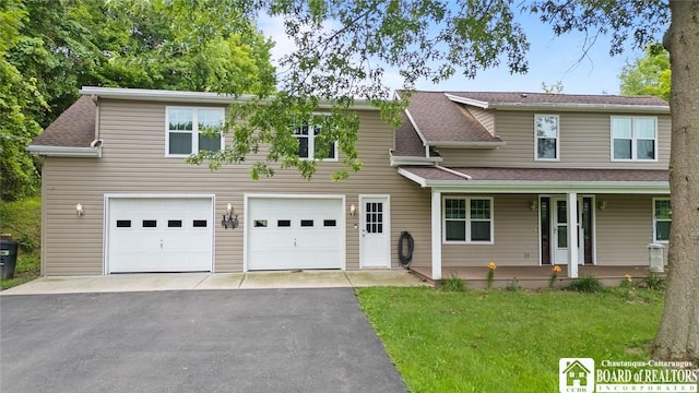 2777 S Roberts Rd, Sheridan, NY 14063 - traditional-style house with an attached garage, asphalt driveway, covered porch, a front lawn, and roof with shingles