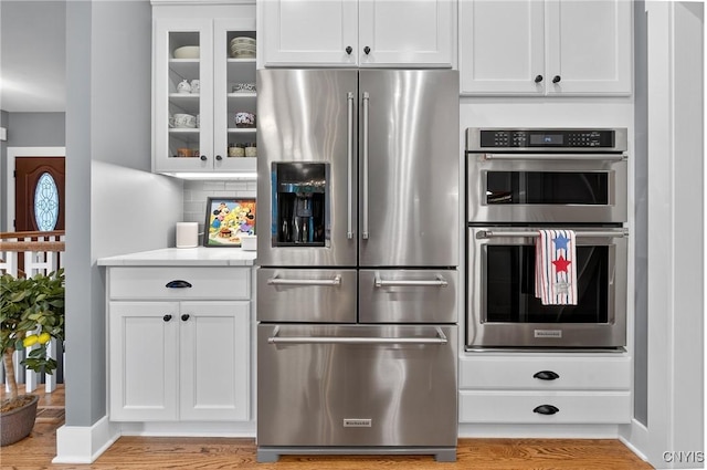 8873 Salvatore Ave, Lysander, NY 13027 - kitchen with stainless steel appliances, glass insert cabinets, light wood-type flooring, and white cabinets