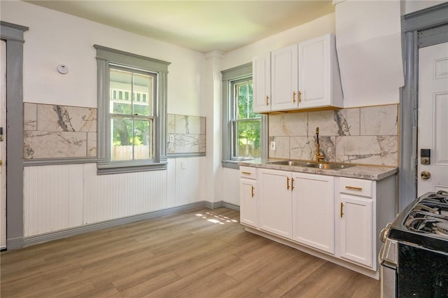 9 Englert St, Rochester, NY 14605 - kitchen featuring stainless steel gas range oven, white cabinets, light wood-type flooring, a wainscoted wall, and decorative backsplash