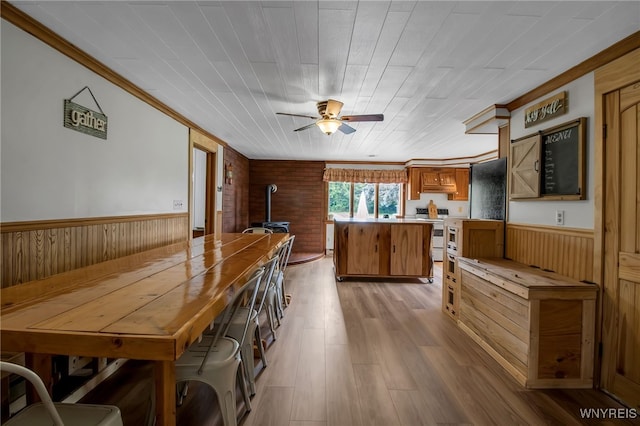 2610 Coomer Rd, Newfane, NY 14028 - kitchen with a wood stove, a center island, wood finished floors, ceiling fan, and brown cabinets