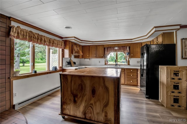 2610 Coomer Rd, Newfane, NY 14028 - kitchen with a baseboard radiator, extractor fan, brown cabinetry, freestanding refrigerator, and light wood-style floors