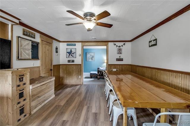 2610 Coomer Rd, Newfane, NY 14028 - dining space with a wainscoted wall, wood walls, ceiling fan, crown molding, and wood finished floors