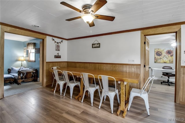 2610 Coomer Rd, Newfane, NY 14028 - dining space featuring a ceiling fan, a wainscoted wall, ornamental molding, wood finished floors, and wooden walls