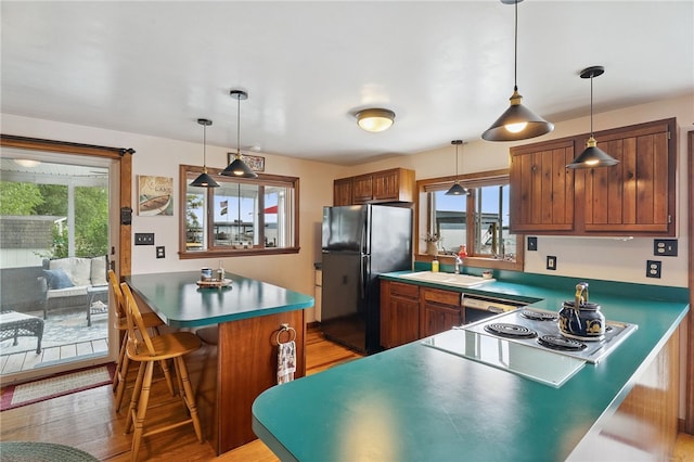 5041 Mapes Mathews Rd, Hector, NY 14818 - kitchen with freestanding refrigerator, light wood-style floors, a breakfast bar area, brown cabinetry, and a peninsula