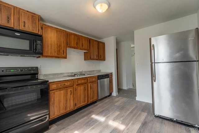 8405 Winterberry Way, Clay, NY 13090 - kitchen with black appliances, light countertops, light wood-type flooring, and brown cabinetry