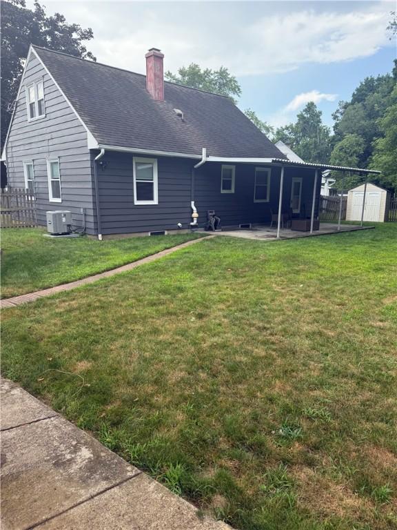 82 Winsor Cir, Elmira, NY 14905 - rear view of property featuring a storage unit, a chimney, a patio area, and roof with shingles