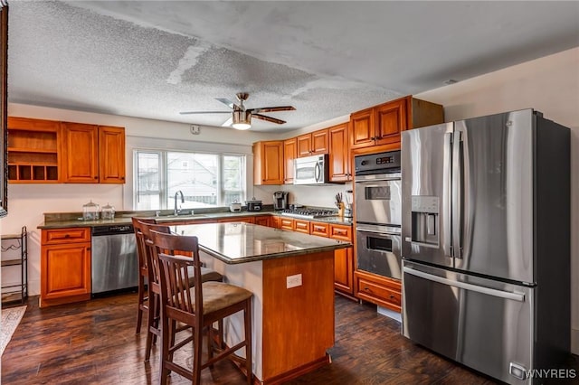 1143 Kensington Ave, Buffalo, NY 14215 - kitchen with stainless steel appliances, brown cabinetry, dark countertops, and a textured ceiling