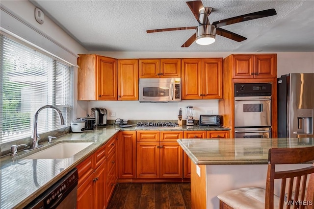 1143 Kensington Ave, Buffalo, NY 14215 - kitchen featuring stainless steel appliances, a textured ceiling, dark wood-style flooring, a breakfast bar, and ceiling fan