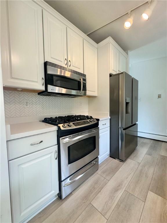12017 Birch Dr, Corning, NY 14830 - kitchen with appliances with stainless steel finishes, a baseboard heating unit, light countertops, and light wood-style floors