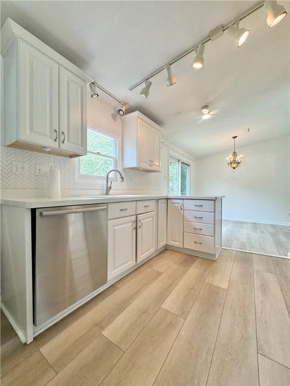12017 Birch Dr, Corning, NY 14830 - kitchen with stainless steel dishwasher, white cabinetry, light wood-type flooring, a peninsula, and light countertops