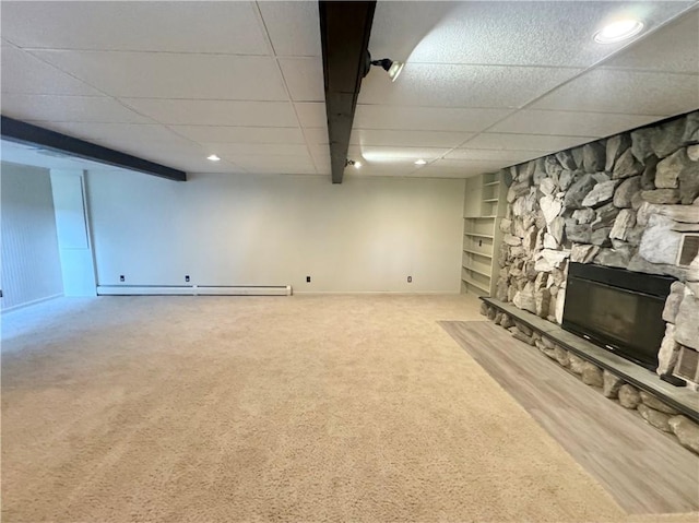 12017 Birch Dr, Corning, NY 14830 - finished below grade area featuring carpet, a drop ceiling, a stone fireplace, built in shelves, and a baseboard radiator