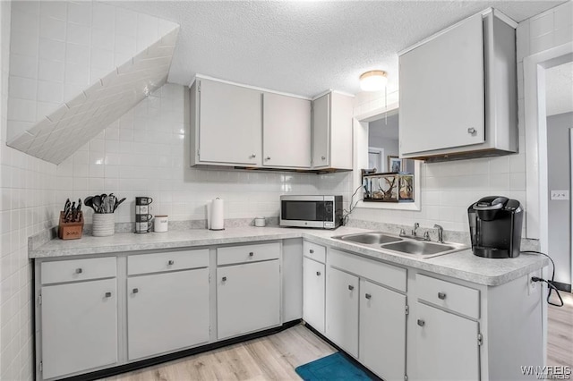 40 Remington Pl, Buffalo, NY 14210 - kitchen with stainless steel microwave, light countertops, light wood-style flooring, a textured ceiling, and tile walls