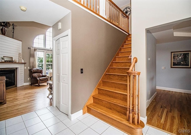 7991 Austrian Pine Cir, Pompey, NY 13104 - staircase featuring a towering ceiling, tile patterned flooring, and a fireplace