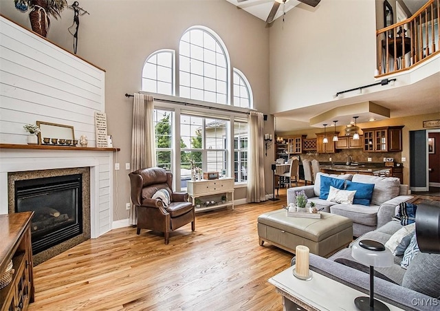 7991 Austrian Pine Cir, Pompey, NY 13104 - living area featuring a high ceiling, light wood-type flooring, a ceiling fan, and a glass covered fireplace
