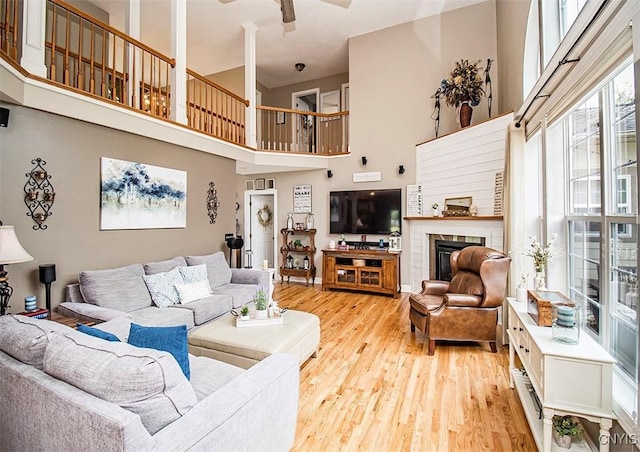 7991 Austrian Pine Cir, Pompey, NY 13104 - living area with a towering ceiling, light wood finished floors, a glass covered fireplace, and a ceiling fan