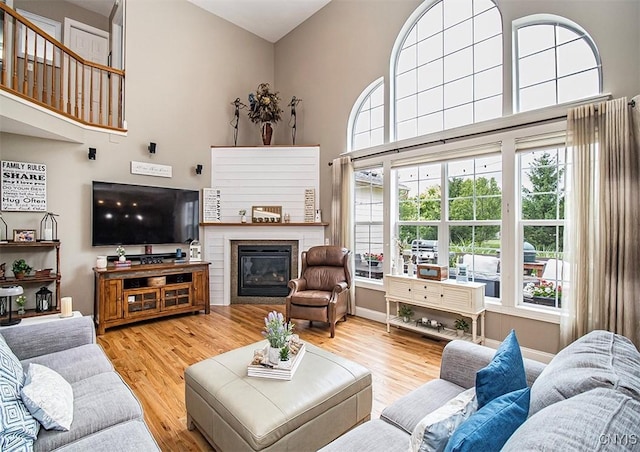 7991 Austrian Pine Cir, Pompey, NY 13104 - living room with wood finished floors, a high ceiling, and a glass covered fireplace