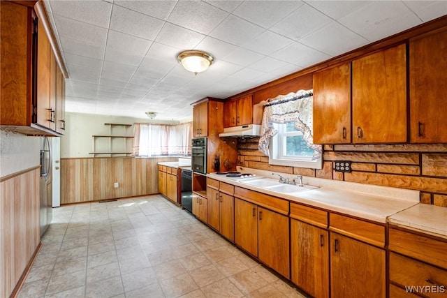 5910 Edgewood Dr, Niagara, NY 14304 - kitchen with healthy amount of natural light, under cabinet range hood, oven, light countertops, and a wainscoted wall