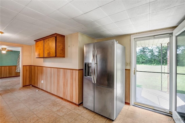 5910 Edgewood Dr, Niagara, NY 14304 - kitchen with stainless steel fridge, wainscoting, ceiling fan, brown cabinetry, and wooden walls