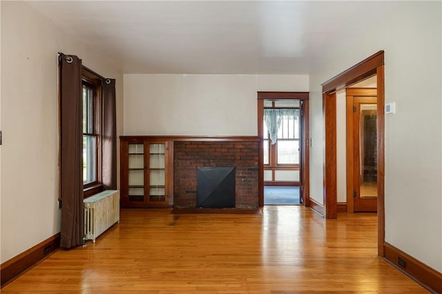 1995 Grand Central Ave, Horseheads, NY 14845 - unfurnished living room featuring radiator heating unit, light wood-style flooring, and a brick fireplace
