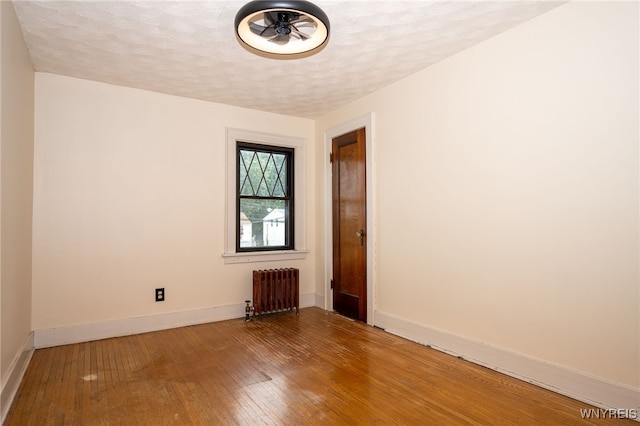 2912 Eggert Rd, Tonawanda, NY 14150 - spare room with radiator heating unit, hardwood / wood-style floors, and a textured ceiling