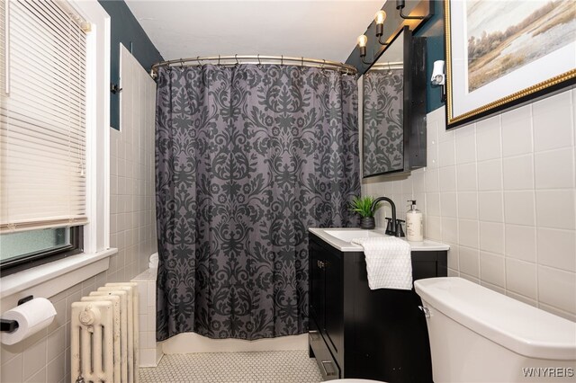 2912 Eggert Rd, Tonawanda, NY 14150 - bathroom with tile walls, radiator heating unit, vanity, and shower / bath combo with shower curtain