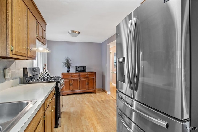 511 Drexler St, Salina, NY 13088 - kitchen with stainless steel appliances, brown cabinetry, under cabinet range hood, light wood finished floors, and decorative backsplash