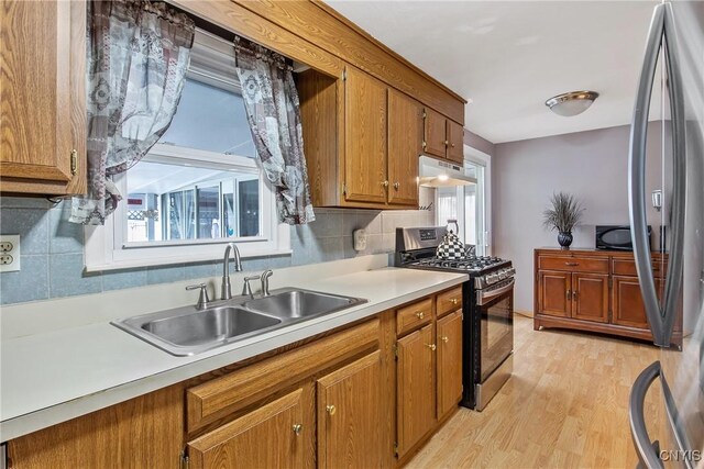 511 Drexler St, Salina, NY 13088 - kitchen featuring stainless steel appliances, under cabinet range hood, brown cabinetry, light countertops, and tasteful backsplash