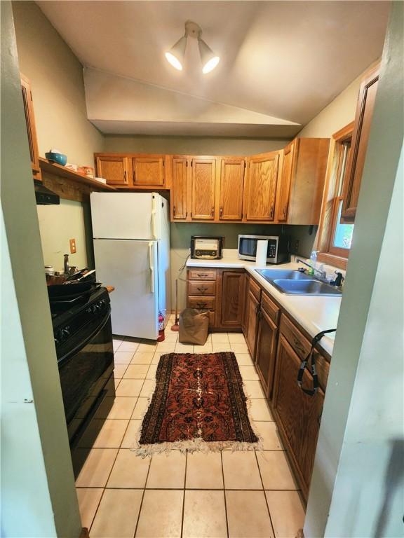 142 John Smith Rd, Pharsalia, NY 13844 - kitchen with freestanding refrigerator, stainless steel microwave, black range, vaulted ceiling, and light countertops