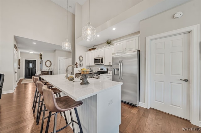 9443 Heritage Path Unit B, Clarence, NY 14032 - kitchen featuring appliances with stainless steel finishes, a breakfast bar area, an island with sink, dark wood-style flooring, and white cabinets