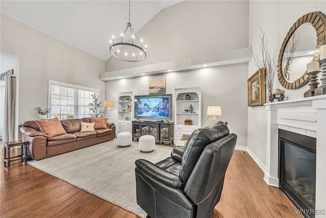 9443 Heritage Path Unit B, Clarence, NY 14032 - living room featuring a chandelier, high vaulted ceiling, a glass covered fireplace, and wood finished floors