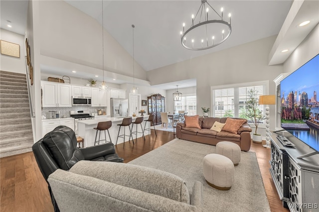 9443 Heritage Path Unit B, Clarence, NY 14032 - living area featuring wood finished floors, high vaulted ceiling, a chandelier, stairs, and recessed lighting