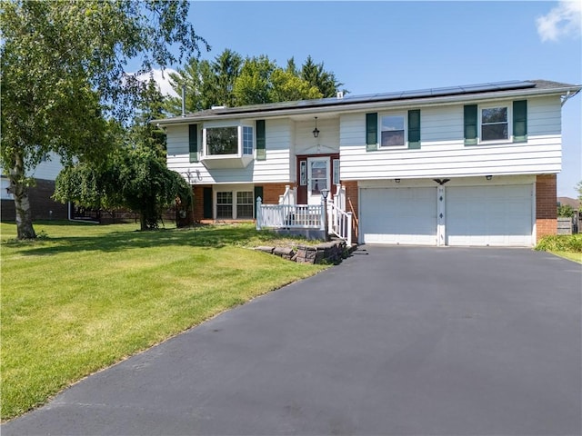 55 Wegman St, Sennett, NY 13021 - raised ranch featuring brick siding, asphalt driveway, roof mounted solar panels, and a garage