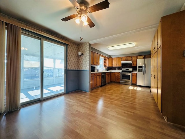 55 Wegman St, Sennett, NY 13021 - kitchen featuring stainless steel appliances, brown cabinetry, light wood-style floors, wallpapered walls, and light countertops
