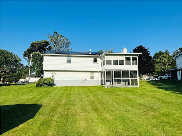 55 Wegman St, Sennett, NY 13021 - rear view of property with a sunroom, roof mounted solar panels, a yard, and a chimney
