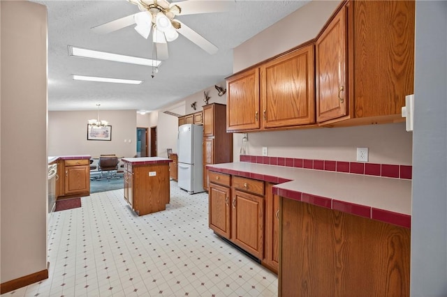 7219 Apple St, Bath, NY 14810 - kitchen featuring freestanding refrigerator, brown cabinetry, a chandelier, and ceiling fan