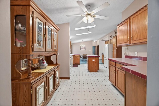 7219 Apple St, Bath, NY 14810 - kitchen featuring freestanding refrigerator, ceiling fan, brown cabinetry, light flooring, and a textured ceiling