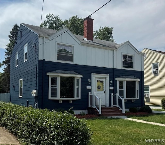129 Brookside Dr, West Seneca, NY 14220 - view of front facade with board and batten siding, a front lawn, and a chimney