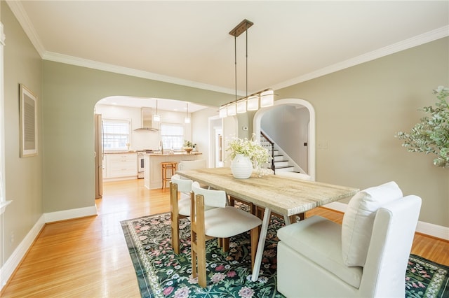 441 Claybourne Rd, Brighton, NY 14618 - dining room featuring arched walkways, light wood-style floors, ornamental molding, and stairs