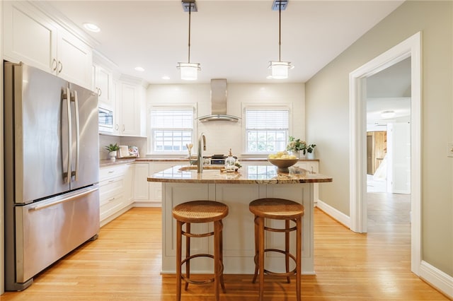 441 Claybourne Rd, Brighton, NY 14618 - kitchen featuring appliances with stainless steel finishes, wall chimney range hood, light wood finished floors, white cabinets, and a kitchen island with sink