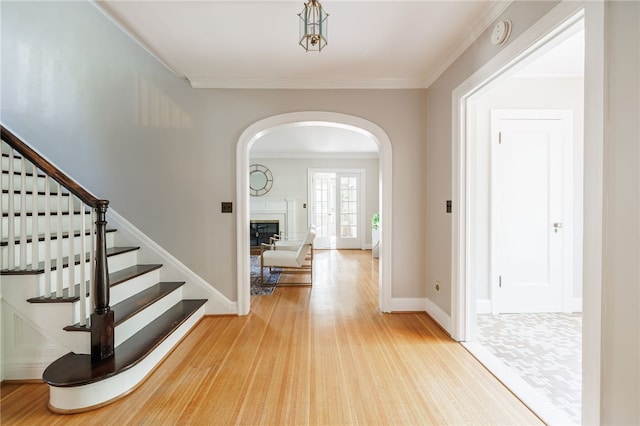 441 Claybourne Rd, Brighton, NY 14618 - foyer entrance featuring arched walkways, stairs, light wood-style floors, a glass covered fireplace, and crown molding