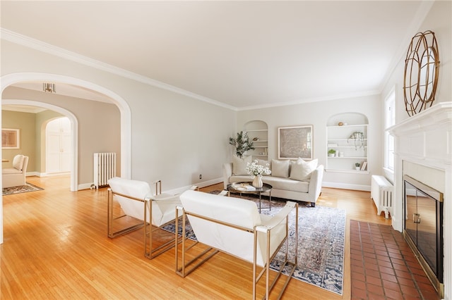441 Claybourne Rd, Brighton, NY 14618 - living room featuring built in shelves, radiator, arched walkways, a fireplace with flush hearth, and crown molding