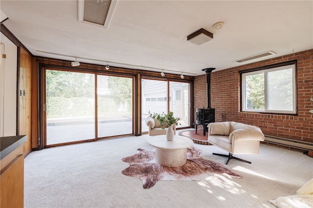 441 Claybourne Rd, Brighton, NY 14618 - sitting room featuring a wood stove, brick wall, carpet flooring, track lighting, and a baseboard radiator