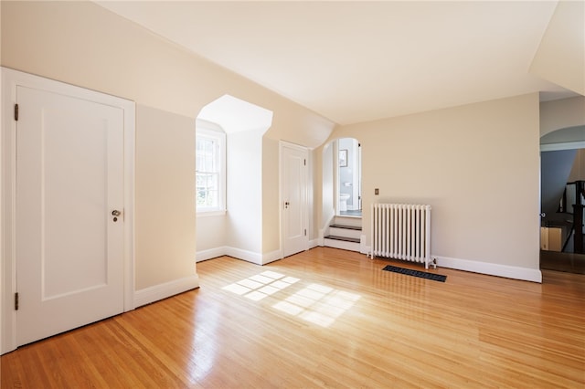 441 Claybourne Rd, Brighton, NY 14618 - unfurnished living room featuring arched walkways, radiator, and wood finished floors