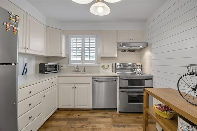 72 Old Lyme Dr Unit 3, Amherst, NY 14221 - kitchen featuring appliances with stainless steel finishes, under cabinet range hood, white cabinets, light countertops, and wood finished floors