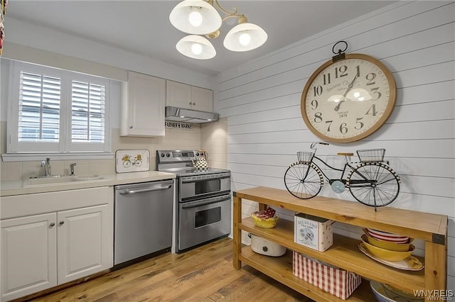 72 Old Lyme Dr Unit 3, Amherst, NY 14221 - kitchen with appliances with stainless steel finishes, under cabinet range hood, a chandelier, wood walls, and light countertops