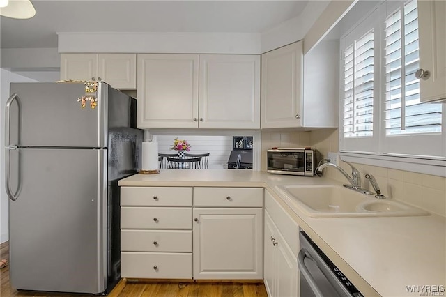 72 Old Lyme Dr Unit 3, Amherst, NY 14221 - kitchen featuring stainless steel appliances, white cabinets, light countertops, light wood-style flooring, and backsplash