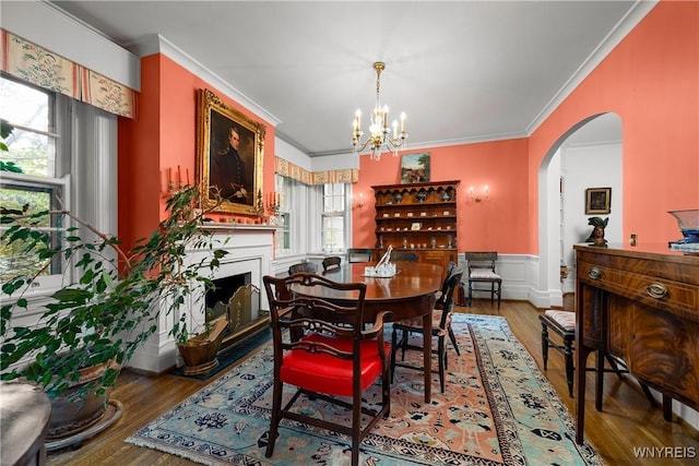 107 Oakland Pl Unit 1, Buffalo, NY 14222 - dining area with arched walkways, crown molding, a fireplace with flush hearth, a chandelier, and a wainscoted wall