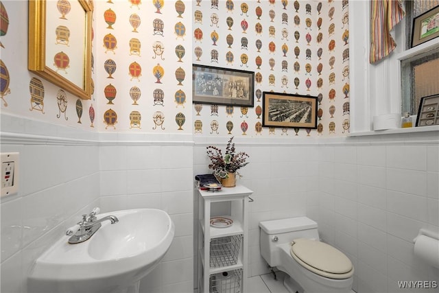 107 Oakland Pl Unit 1, Buffalo, NY 14222 - half bathroom featuring wainscoting, tile walls, wallpapered walls, and tile patterned floors